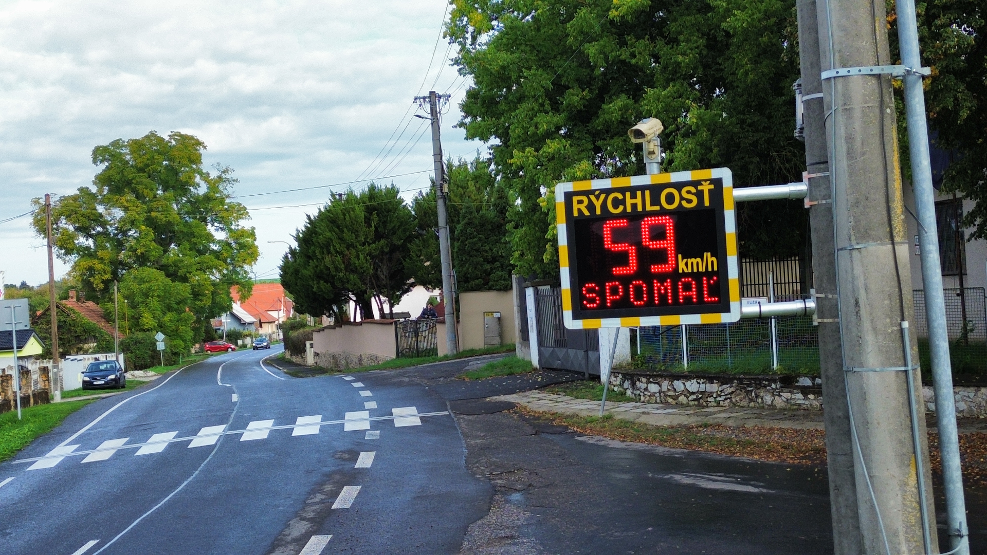 Merač rýchlosti BELLIMPEX s výzvou SPOMAĽ pri priechode pre chodcov.