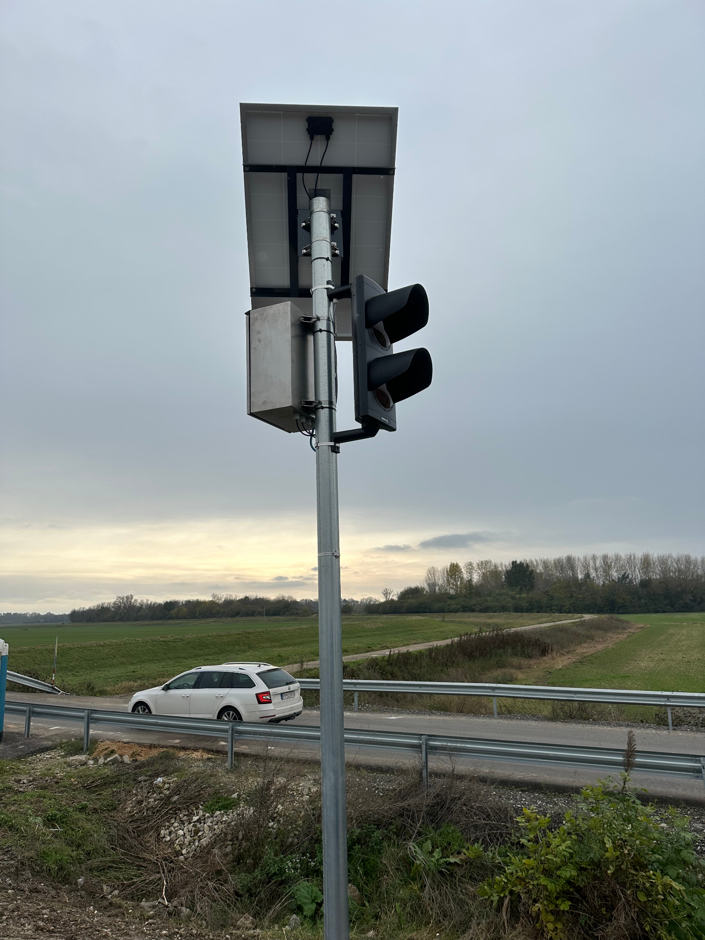 Pohľad zdola na solárny semafor BELLIMPEX – fotovoltický panel a LED návestidlá nad cestou.